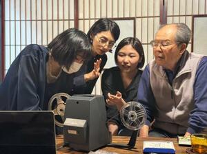 「地域映画」の制作に向け、フィルム提供者(右)や大学生スタッフと映像を確認するプロデューサーの三好祐子さん(左から2人目)=2024年4月、長野県松本市(まつもとフィルムコモンズ提供)