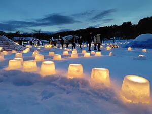 ろうそくの柔らかな光に包まれた雪ほたるの会場=関川村安角