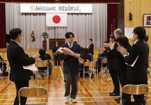 贈られた花束を手に退場する高田高校安塚分校の最後の卒業生=3月4日、上越市安塚区下方