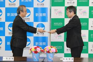 花角英世知事(左)から目録を受け取る新潟大の牛木辰男学長=4月8日、県庁