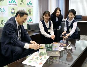 広報誌などを囲んで話す遠藤一雄・経営管理委員会副会長(左)と組織広報課員=新潟市西蒲区のJA新潟かがやき本店