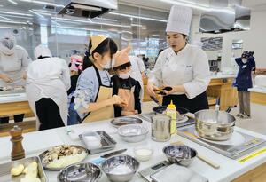 専門学校生のアドバイスを受けながら料理を作る子ども=新発田市諏訪町1