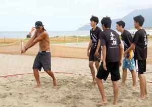 中越高校男子バレーボール部の生徒に指導する同校OBでプロビーチバレー選手の長谷川徳海さん(左)=8月24日、長岡市寺泊地域の海水浴場