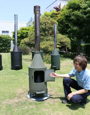 ホンマ製作所の藤井孝さんが説明するガーデンストーブ=新潟市南区