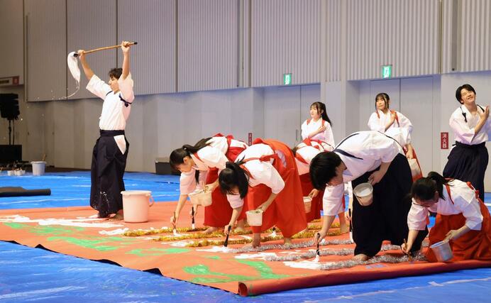 大きな筆を使ったパフォーマンスを披露する東京学館新潟高校の書道部員＝４日、新潟市中央区