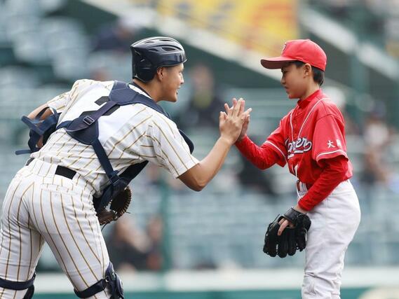 始球式を務めた子どもとハイタッチする帝京長岡の捕手松本覇＝２３日、阪神甲子園球場