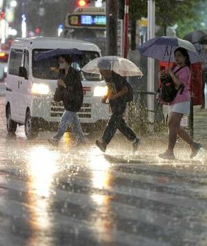 大雨の中、傘を差して歩く人たち=10日、東京・池袋