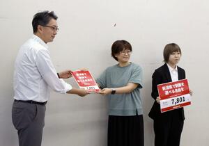 県教育委員会の石山崇課長（左）に署名数が書かれた紙を提出するにじーず新潟のメンバー＝９月２日、新潟市中央区
