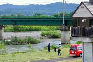 石狩川の河川敷を調べる警察官ら=23日午後4時30分ごろ、北海道旭川市川端町