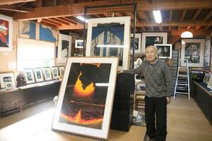 落ち着いた雰囲気の「アトリエ佐輝」で、作品の横に立つ市橋輝之さん=佐渡市加茂歌代