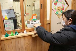 コドモンの専用端末にQRをかざし、降園時の打刻をする保護者=上越市有間川のたにはま保育園