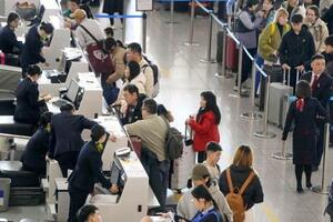 　春節の帰省や旅行に伴う特別輸送態勢「春運」が始まり、北京首都国際空港の日本便を扱うカウンターで搭乗手続きをする人たち＝２日（共同）