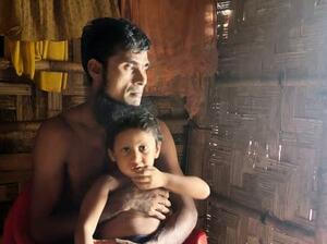 子どもを抱くジアブ・ラーマンさん=7月、バングラデシュ・コックスバザール(共同)