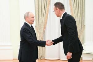 　４日、モスクワのクレムリンで握手するロシアのプーチン大統領（左）とハンガリーのシーヤールトー外務貿易相（タス＝共同）
