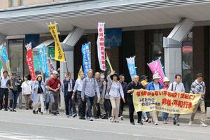 のぼりなどを手に核廃絶などを訴えながら歩く非核・平和行進の参加者=12日、新潟市中央区