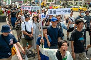 23日、台北市の繁華街を行進するデモ参加者ら(共同)