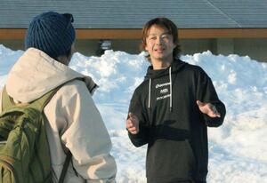 国際スノーボード＆スケートボード専門学校の同僚と打ち合わせする滝沢光さん＝妙高市原通