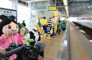 北陸新幹線の乗客に手を振って出迎えるご当地ゆるキャラら=3月16日、糸魚川市のJR糸魚川駅