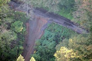 国道４０５号が崩落し、乗用車１台が転落した現場＝１７日、津南町結東（新潟日報社ヘリから）

