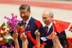 歓迎式典に臨むロシアのプーチン大統領(奥右)と中国の習近平国家主席の前で振られる両国の国旗=20日、北京の人民大会堂(共同)