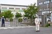 　クマに従業員が襲われた「福島製鋼」事業所の入り口付近で警戒する警察官や関係者＝２日午前８時５４分、福島市
