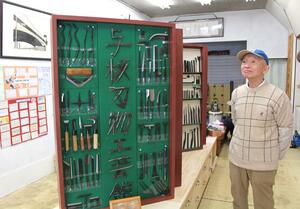 展示棚に飾った打刃物を見つめる川野正さん。「頼まれれば何でも作った」という製品は多種多様だ=長岡市与板町与板