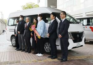 県遊技業協同組合の寄付金を活用して購入した福祉車両の前に立つ関係者＝新潟市中央区