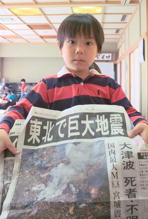 震災翌日の２０１１年３月１２日、福島市内の避難所で新聞を手にする荒木田陸さん