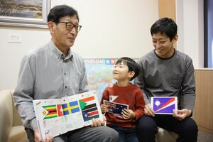 国旗検定1級に合格し笑顔を見せる祖父の齋木正美さん(左)と孫の漣ちゃん(中央)。右は父航さん=新潟市中央区