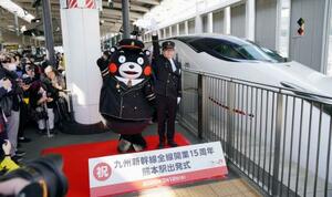　九州新幹線全線開業１５周年を記念した出発式で、出発の合図を送る熊本県ＰＲキャラクター「くまモン」ら＝１２日午前、ＪＲ熊本駅