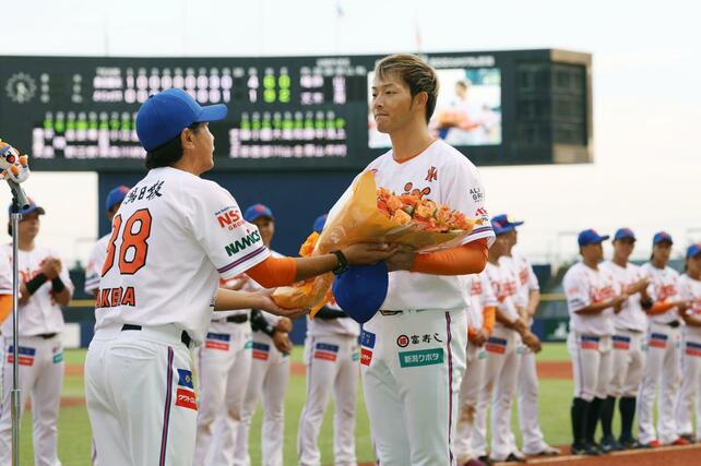 最終戦セレモニーで武田勝監督から花束を受け取る藪田和樹選手。今季限りで退団する＝エコスタ