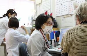 キツネをイメージしたマスクと耳を付けて診察する病院スタッフと外来患者=阿賀町津川