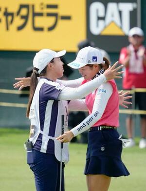 優勝し、キャディーを務めた吉田弓美子(左)から祝福される桜井心那=大箱根CC