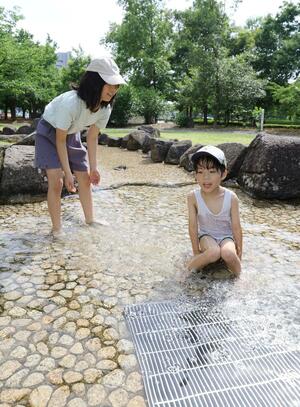照りつける日差しを背に、元気に水遊びする子供たち=6月15日、長岡市千秋3