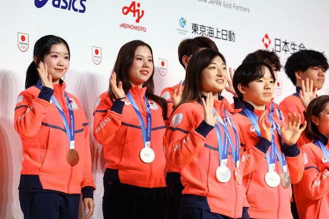 帰国後の記者会見で、手を振るフィギュアスケート女子銅メダリストの中井亜美選手（左端）ら＝東京都内のホテル