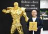漫画「北斗の拳」の主人公ケンシロウの黄金像と写真に納まる、原作者の武論尊さん＝３日午前、名古屋市の松坂屋名古屋店