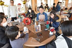 「テイク布リー」の布やひもを使ってクリスマスツリーを作る家族連れら=見附市本所2