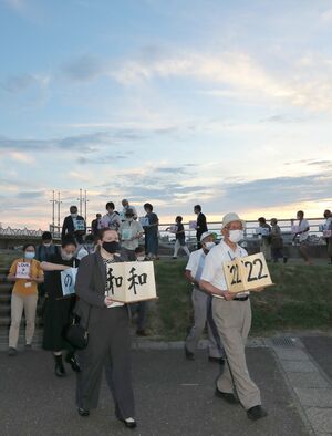 平和を祈り、夕暮れの公園内を行進する参加者=8月11日、上越市川原町
