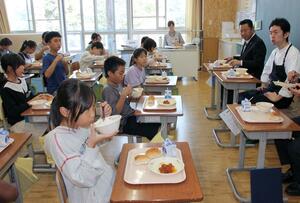 赤倉観光ホテルの小黒正之料理長（右）らと市制２０周年記念給食を味わう児童＝妙高市の新井小