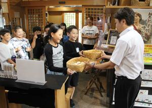 狐の嫁入り屋敷に、オリジナルラベルの雪椿塩を納品する児童＝阿賀町津川