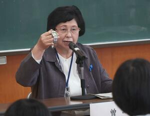 拉致される前にミヨシさんに買ってもらった時計を見せながら講演する、曽我ひとみさん=8日、佐渡市