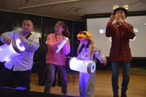 イベントで歌うかしわ哲さん(右端)と「ハグドラム」などを演奏する参加者=2025年12月、東京都品川区