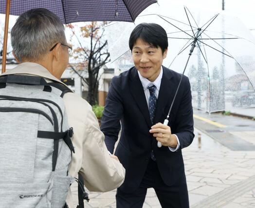 市民と握手する梅谷守さん＝上越市