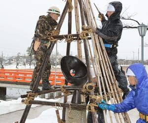 手際よくブロンズ像の冬囲いを外す作業員ら=3月6日、上越市本城町