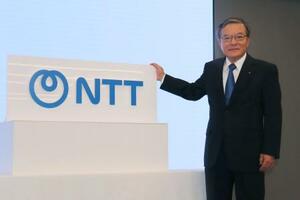 「NTT」への社名変更に伴う式典で、ロゴと写真に納まる島田明社長=1日午前、東京都内