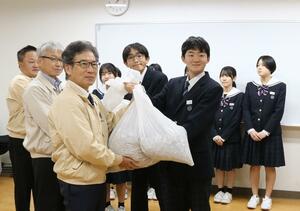 集めたプルトップを三条中央ライオンズクラブへ引き渡す大崎学園の生徒(右)=三条市東大崎1