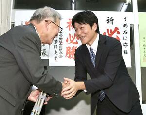 当確の知らせを受け、支持者らと握手し、喜びを分かち合う梅谷守さん(右)=10月27日午後9時前、上越市木田1