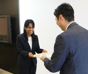 大和証券新潟支店の石本靖朗支店長(右)から贈呈書を受け取る新潟大のマドシカ助教=新潟市中央区
