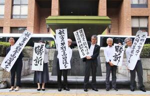 三重県4市の生活保護減額訴訟の控訴審判決後、「勝訴」などと書かれた垂れ幕を掲げる原告団の弁護士ら=26日午後、名古屋高裁前