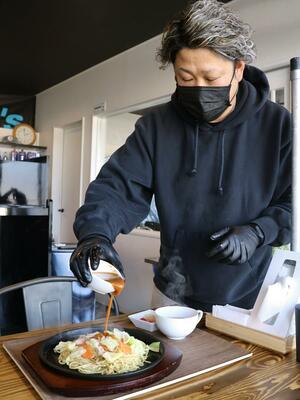メニューの「焼麺」を提供する圡田一幾さん。客の前でソースをかける演出がポイント＝加茂市幸町１